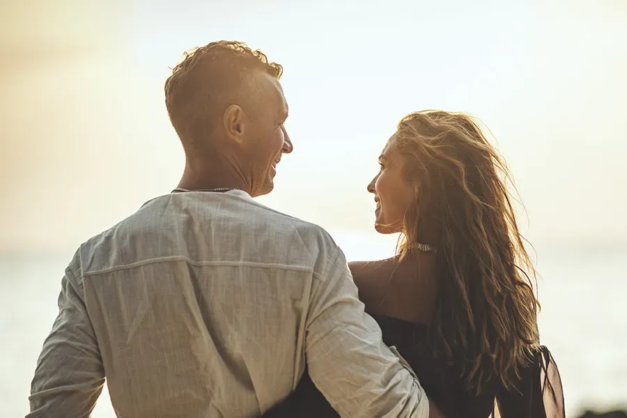 Anti-Aging-Clinic A couple gazes at each other on the beach at sunrise, viewed from behind. Schedule Anti-Aging treatment from Scott Gulinson, MD, FACOG in Phoenix.