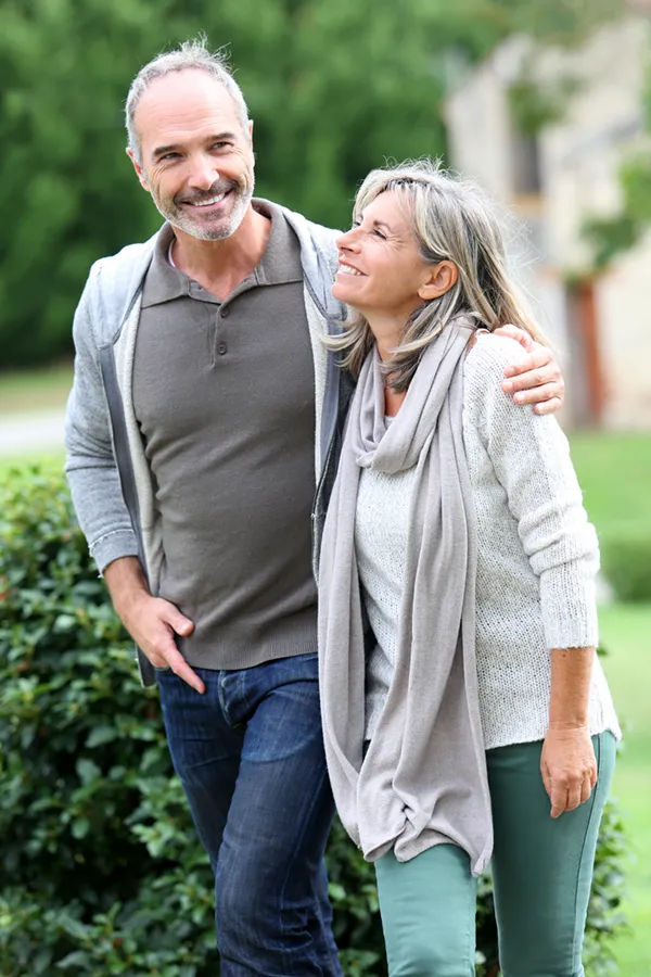 Bioidentical-Hormone-Therapy-Treatment A mature couple in gray toned clothes and jeans walk happily outside, happy with their successful bioidentical hormone treatments from Scott Gulinson, MD, FACOG in Phoenix.