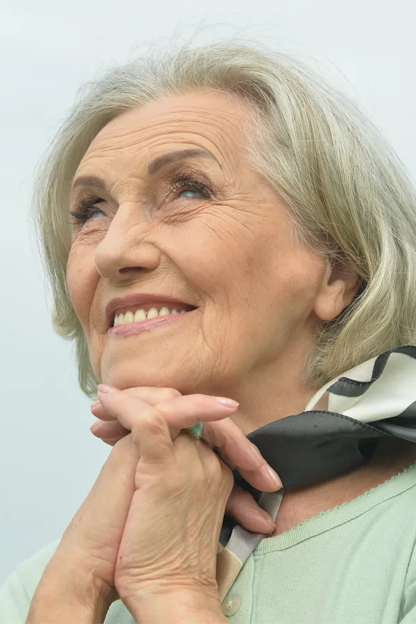 Hot-Flashes-and-Night-Sweats-Treatments An older woman holds her hands together under her chin and looks up at a cool sky smiling. Get treatment for hot flashes and night sweats from Scott Gulinson, MD, FACOG in Phoenix.