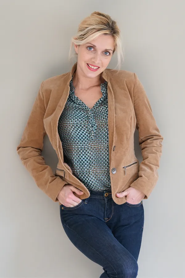 Metabolic-Syndrome-Treatment A smiling blonde woman in a tan leather jacket leans against a gray wall. Schedule metabolic syndrome from Scott Gulinson, MD, FACOG in Phoenix.