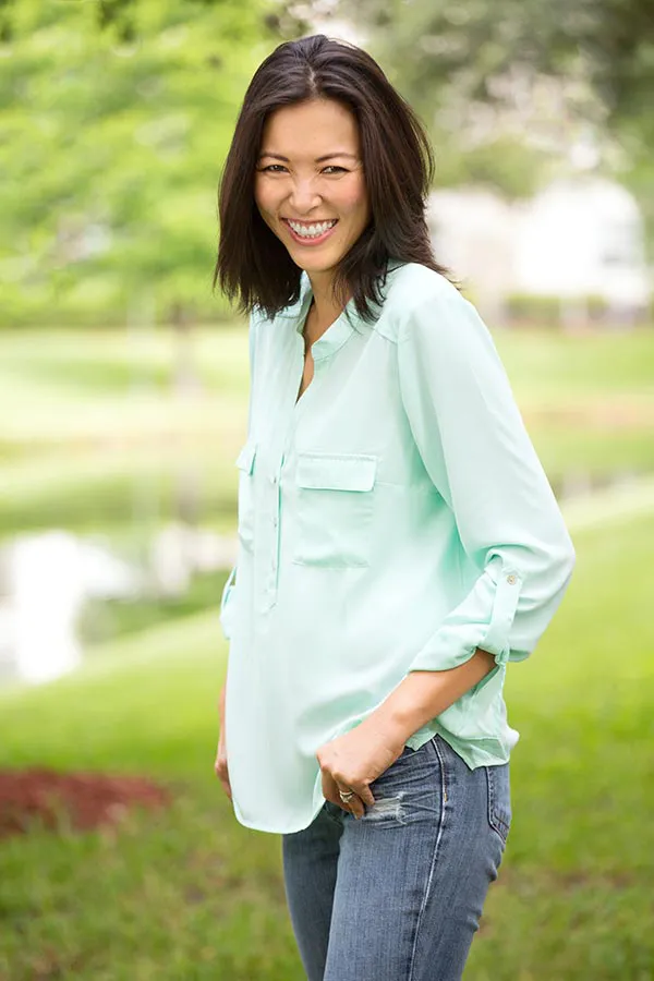 Perimenopause-Treatment A middle-aged brunette woman in a light green button-up shirt stands outside smiling, happy with her perimenopause treatment from Scott Gulinson, MD, FACOG in Phoenix.