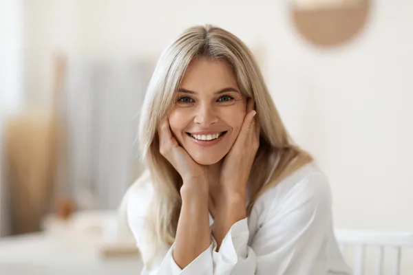 Perineoplasty-Clinic A woman sitting and smiling in her home. Schedule perineoplasty treatment from Scott Gulinson, MD, FACOG in Phoenix.
