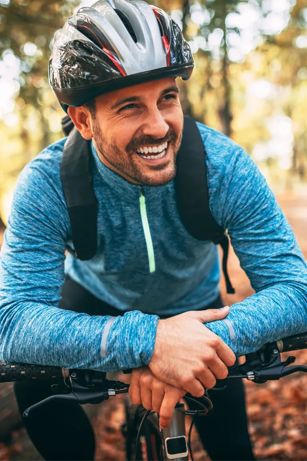 Testosterone-Low-T-Solutions-Treatment A middle-aged man on a trail in cycling clothes is smiling and leaning on his bike's handlebars. Get testosterone for Low T from Scott Gulinson, MD, FACOG in Phoenix.