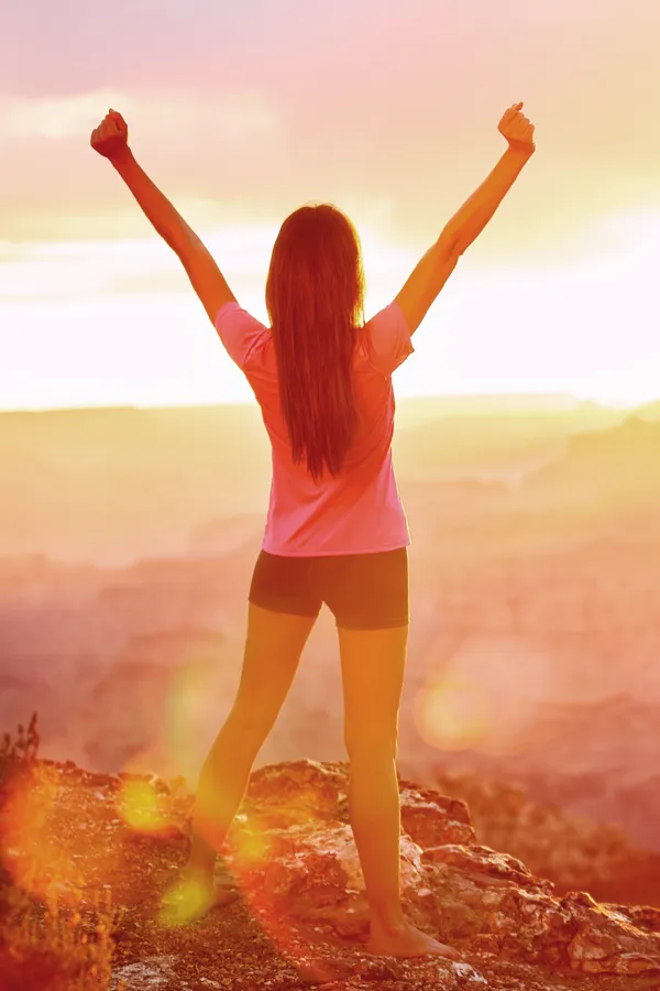 Vulvar-Labiaplasty-Treatment A woman raises her arms in triumph at sunrise. Get vulvar labiaplasty treatment from Scott Gulinson, MD, FACOG in Phoenix.